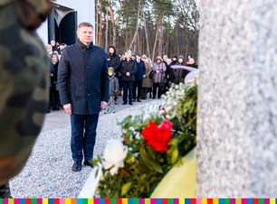 Marek Malinowski stoi przed pomnikiem żołnierza wyklętego.
