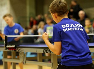 Chłopcy w koszulkach z napisem Dojlidy Białystok grają w tenisa stołowego