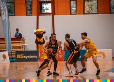 Koszykarze podczas turnieju, w tle maskotka drużyny 