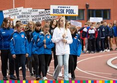 Dziewczęta z powiatu bielskiego idą przez stadion niosąc tabliczki z nazwami szkół