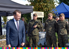 Mariusz Błaszczak, obok trzech żołnierzy, dwóch mężczyzn i kobieta. Jeden z mężczyzn trzyma broń długą.