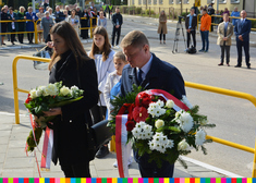 Mężczyzna i kobieta składają kwiaty przed pomnikiem