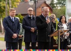 Mężczyzna w czarnym garniturze mówi do mikrofonu. W tle uczestnicy wydarzenia