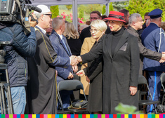 Członek zarządu Wiesława Burnos podaje dłoń mężczyźnie. W tle uczestnicy wydarzenia