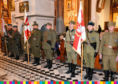 Kilku mężczyzn w mundurach stoi w kościele, trzymają sztandary