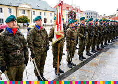 Żołnierze ze sztandarem stoją przed tablicą pamiątkową