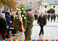 Mężczyzna w mundurze składa wieniec. Wokół niego uczestnicy wydarzenia