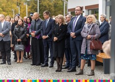 Uczestnicy wydarzenia stoją na placu przed muzeum