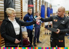 Trener przekazuje członkini zarządu Wiesławie Burnos symboliczne rękawice bokserskie