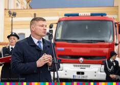 Członkowie zarządu Marek Malinowski mówi na tle czerwonego wozu strażackiego