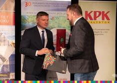 Członek zarządu Marek Malinowski przekazuje mężczyźnie torebkę z żubrem
