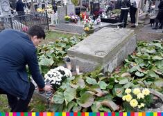 Mężczyzna stawia kwiatki na grobie