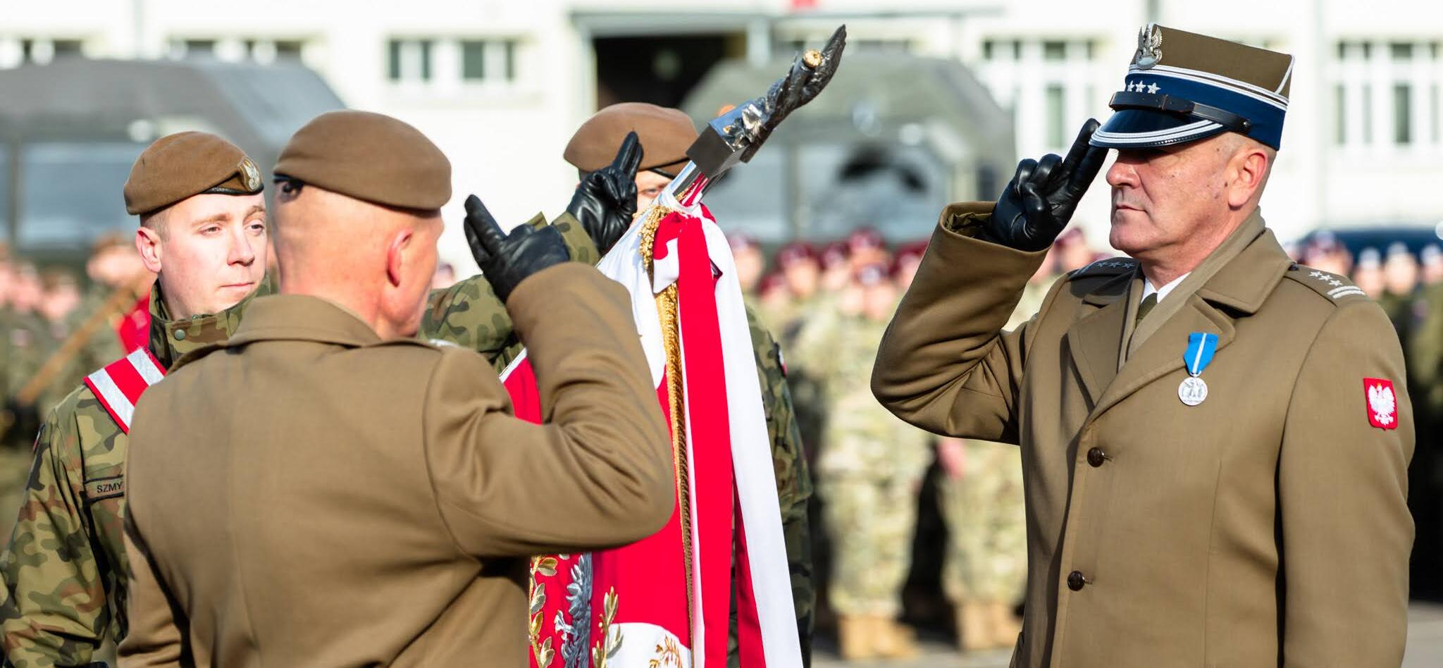 Oficerowie salutują przed pochylonym sztandarem wojskowym