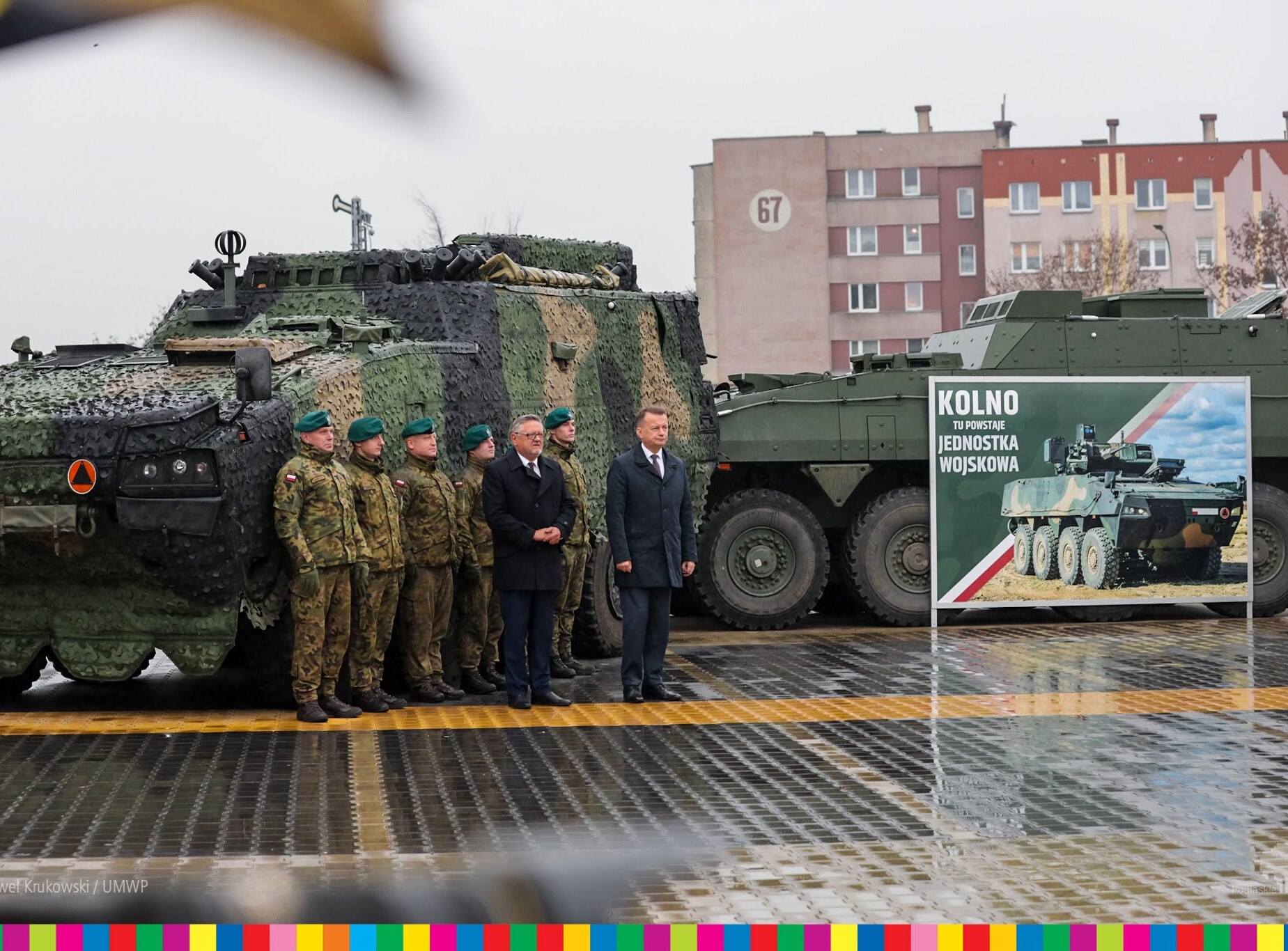 Mężczyźni oraz wojskowi stoją na tle czołgów