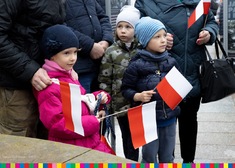 Dzieci z flagami stoją na placu 