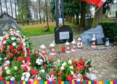 Znicze i kwiaty pod pomnikiem
