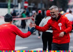 biegnąca kobieta przybija piątkę mężczyznie, organizatorowi biegu 