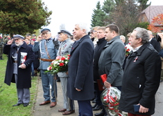 Uczestnicy wydarzenia stoją przed pomnikiem