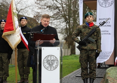 Członek zarządu Marek Malinowski przy mównicy na tle żołnierzy