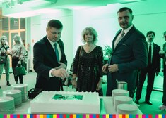 Członek zarządu Marek Malinowski w towarzystwie dwóch osób kroi tort