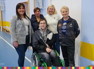 Mężczyzna na wózku inwalidzkim, za nim stoją cztery kobiety