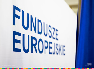 Biała ścianka z niebieskim napisem Fundusze Europejskie