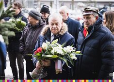 Marszałek Olbryś trzyma kwiaty, stoi wśród uczestników wydarzenia