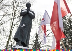 Pomnik ks. Jerzego Popiełuszki i dwie flagi biało-czerwone