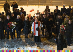 Ksiądz z grupą ludzi przed Pomnikiem Katastrofy Smoleńskiej