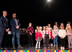 Burmistrz Łap i wicemarszałek Sebastian Łukaszewicz stoją na scenie z dziećmi