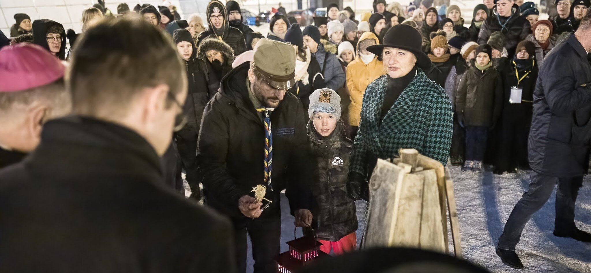 Wiesława Burnos wraz z dzieckiem i harcmistrzem stoja w tłumie na placu