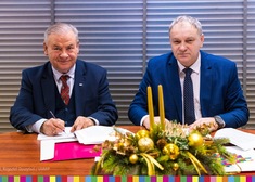 Wicemarszałek Marek Olbryś siedzi obok burmistrza Jedwabnego za stołem z ozdobami świątecznymi