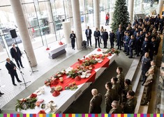 Służby mundurowe stoją wzdłuż stołu w holu opery, naprzeciwko wiceminister i przedstawiciele zarządu województwa