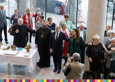 Marszałek Artur Kosicki stoi z osobami duchownymi i seniorami