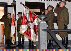 mężczyźni w mundurach trzymają sztandar w barwach biało-czerwonych 