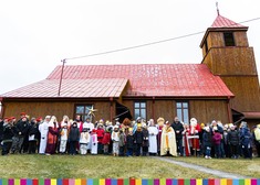 Grupa osób w przebraniach stoi na zdjęciu grupowym na tle kościoła