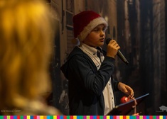 Chłopiec w czapce Mikołaja podczas śpiewu.