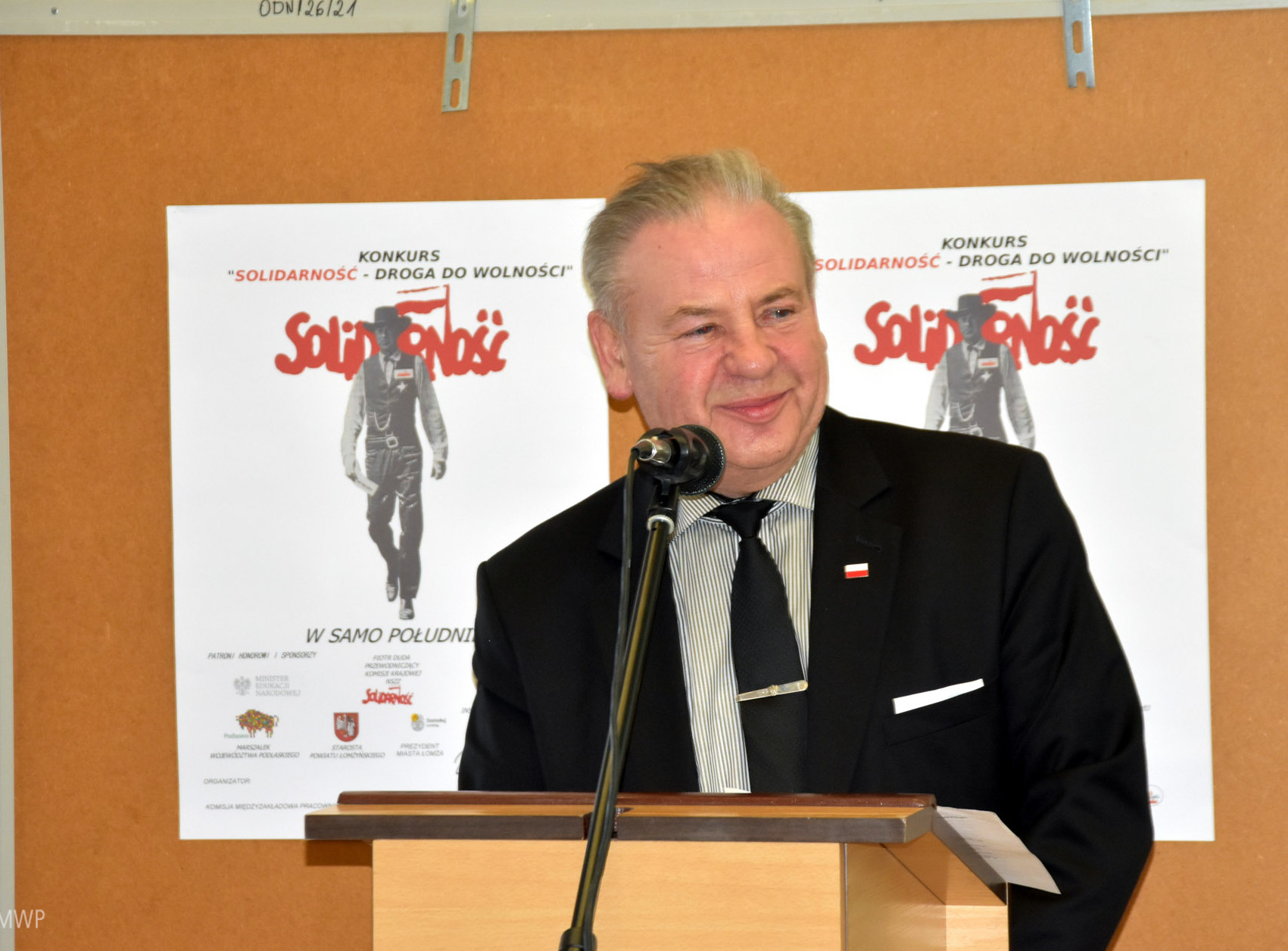 wicemarszałek Marek Olbryś przy mównicy, za nim znajduje się plakat konkursowy z napisem Solidarność