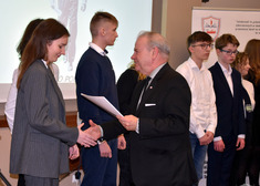 wicemarszałek Marek Olbryś podaje dłoń młodej dziewczynie, w ręku trzyma dyplomy, obok nich stoi młodzież
