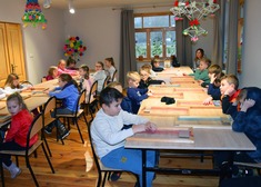 Dzieci uczą się tkać siedząc przy stole