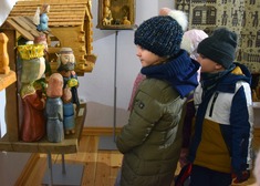 Dziecko przygląda się rzeźbionym figurkom z drewna