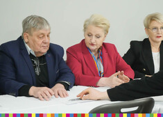 Między dwoma osobami siedzi przy stole Wiesława Burnos, członek zarządu