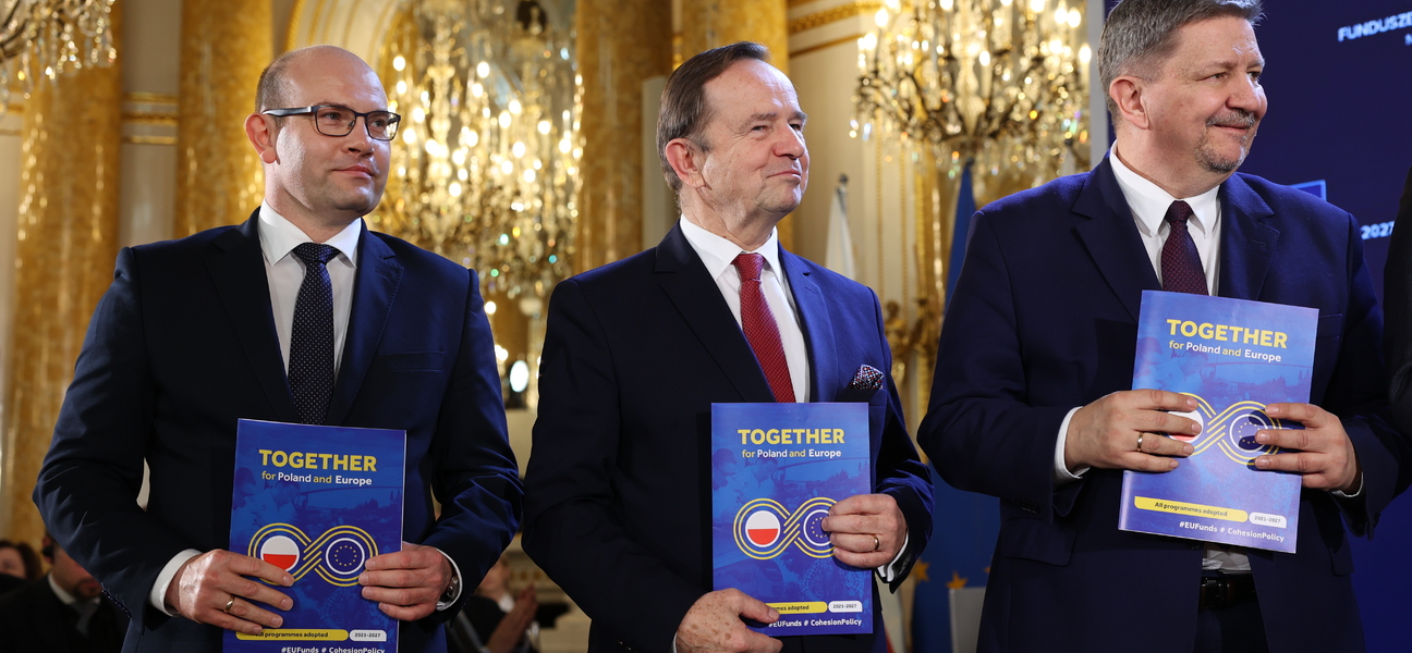 Trzech mężczyzna w garniturach trzyma niebieskie teczki