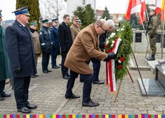 marszałek Artur Kosicki poprawia szarfę przy kwiatach pod pomnikiem ku czci Sybiraków
