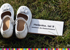 białe dziewczęce buciki leżące na trawie, obok nich znajduje się tabliczka z napisem: Helenka, lat 9, zesłana do Kazhstanu
