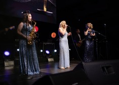 Na scenie trzy kobiety, jedna ghrz na saksofonie, a dwie śpiewają do mikrofonów