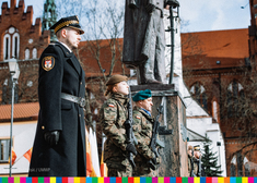Dwoje żołnierzy i strażnik miejski przy pomniku Józefa Piłsudskiego