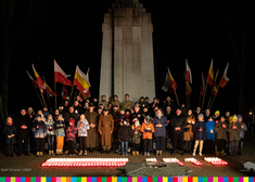 Grupa osób przed pomnikiem.
