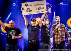 mężczyzna z zespołu Bad Falcon trzyma w górze czek na kwotę 5 tys. zł