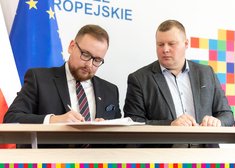Wicemarszałek Sebastian Łukaszewicz w obecności wójta gminy Wyszki składa podpis